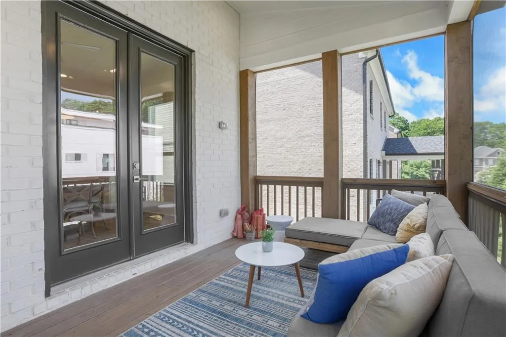 Screened porch featuring wood-finish flooring, white brick exterior wall, and dark-framed double glass doors