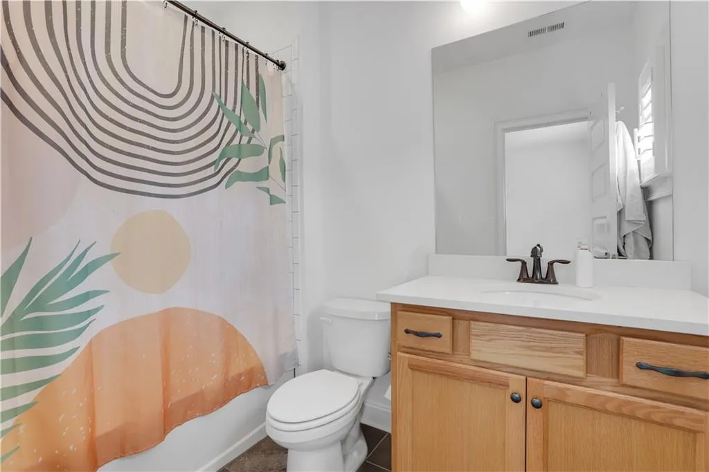 Bathroom featuring a full vanity with wood-finish cabinetry, a white countertop, and an integrated sink with an oil-rubbed bronze faucet