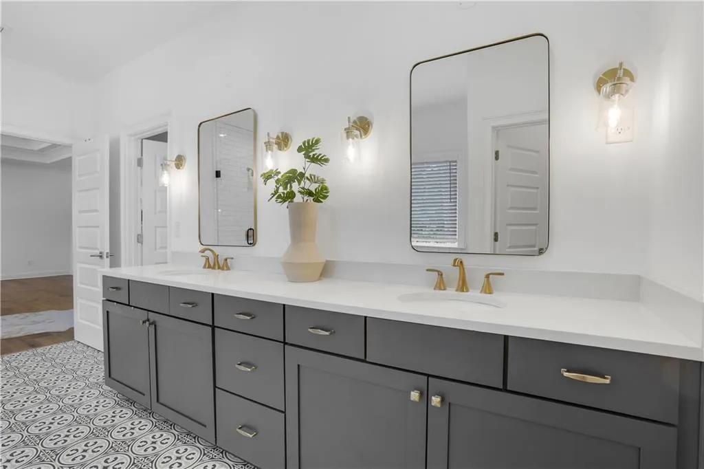 Double vanity featuring gray cabinetry, quartz countertops, gold-finish hardware, and rectangular mirrors