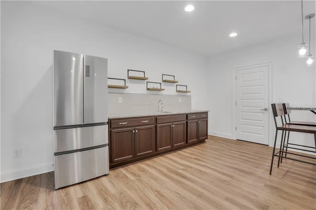 Beverage bar with dark wood cabinetry, light speckled countertop, and a stainless steel refrigerator