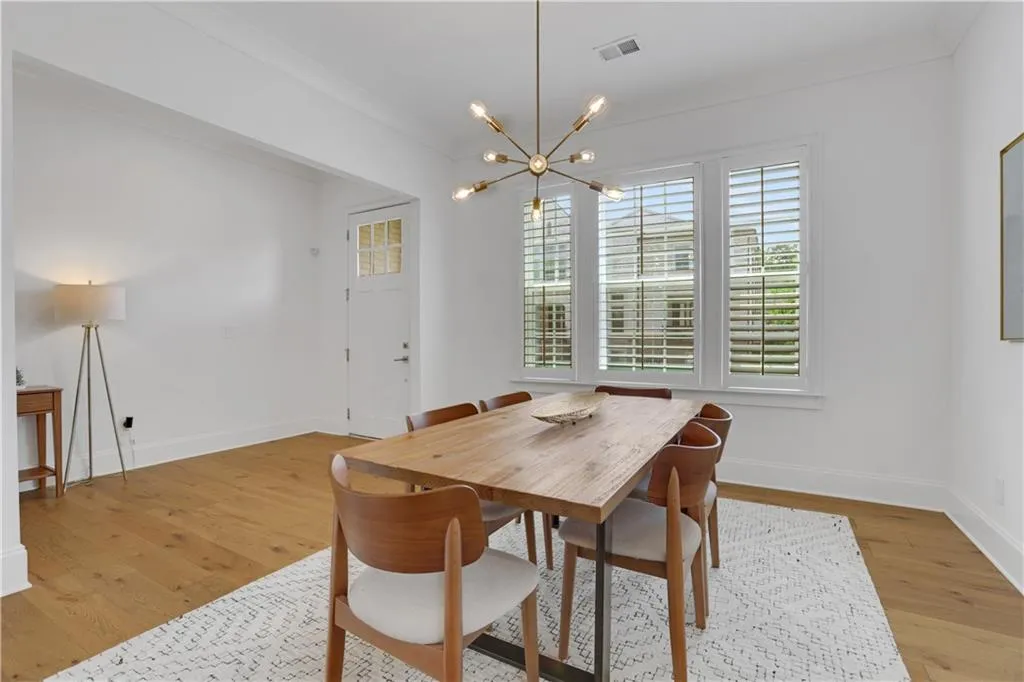 Dining area featuring wood-finish flooring, crisp white walls, and a contemporary chandelier