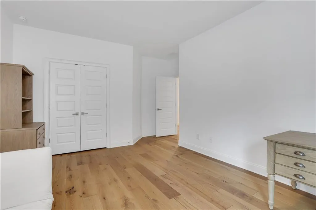 Spacious room featuring wide plank wood-finish flooring, crisp white walls, and elegant white baseboards