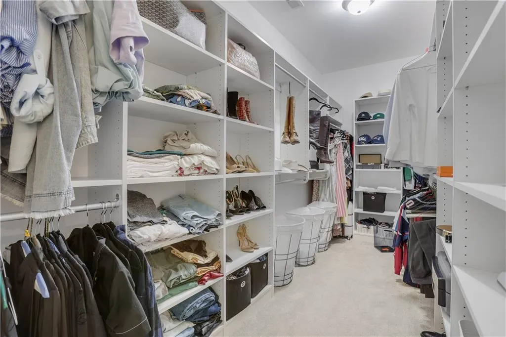 Custom closet system featuring extensive shelving, multiple hanging rods, corner shelving, and recessed lighting