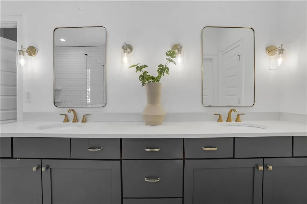 Dual vanity featuring a white countertop, undermount sinks, and gold-finish fixtures
