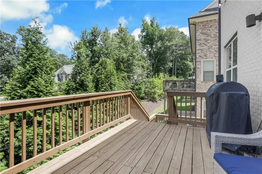 Expansive wood deck with natural wood railings, featuring a brick and white siding exterior