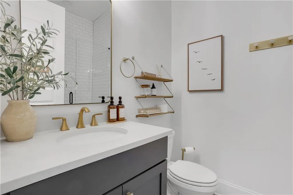 Bathroom vanity featuring an integrated white sink, brushed brass faucet, and grey cabinetry