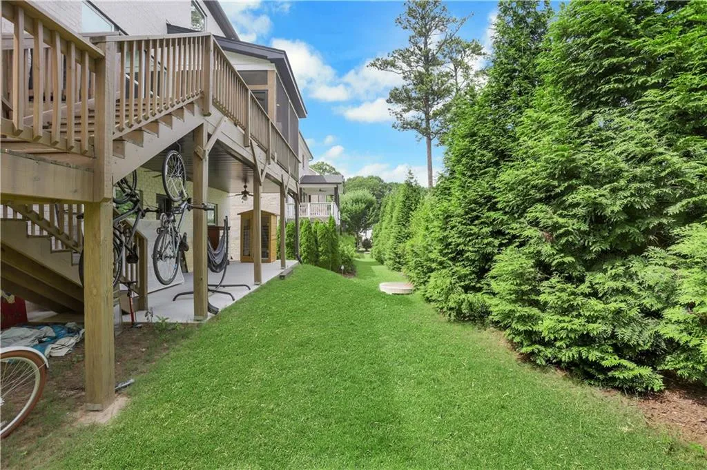 Rear exterior featuring a wooden deck with railing, a screened porch, and a patio area beneath the deck