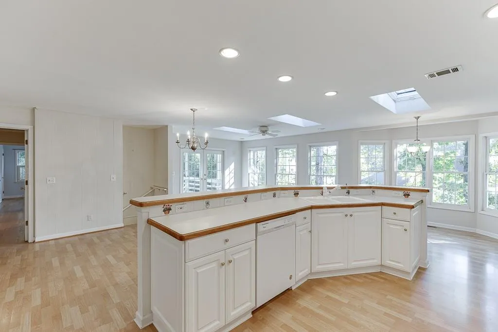 Kitchen with skylights, light wood-style flooring, a sink, a skylight, and dishwasher