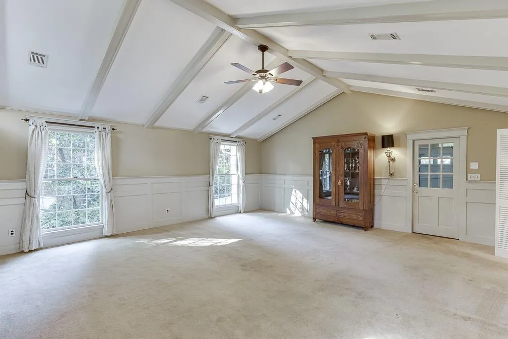 Bonus room featuring lofted ceiling with beams, carpet, visible vents, and wainscoting