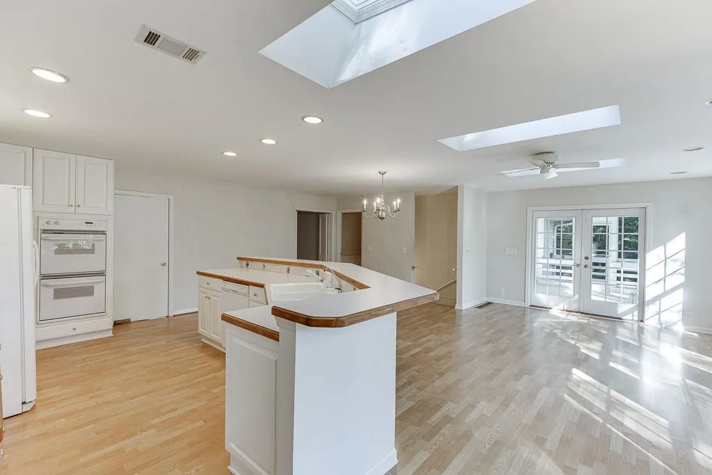 Kitchen featuring skylights , light wood-style flooring, a skylight, white appliances, and a sink