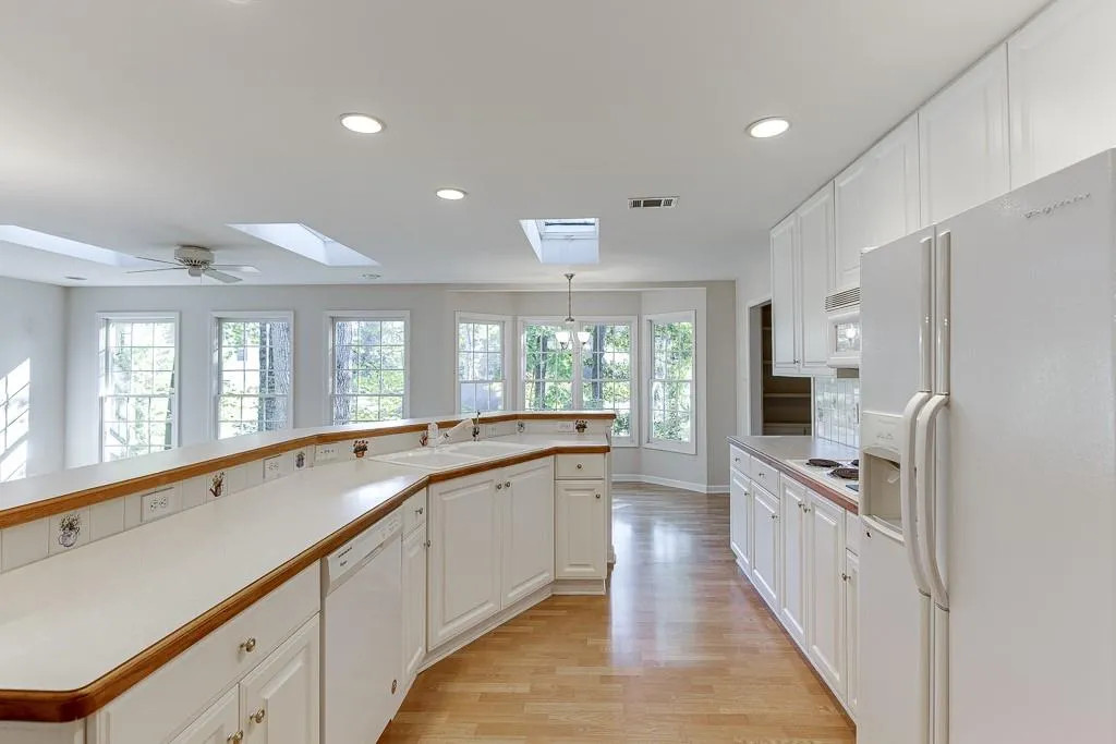 Kitchen featuring white appliances, a healthy amount of sunlight, visible vents, a skylight, and a sink