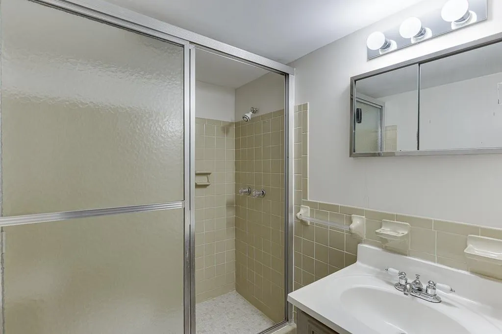 Full bathroom with a stall shower, vanity, and tile walls