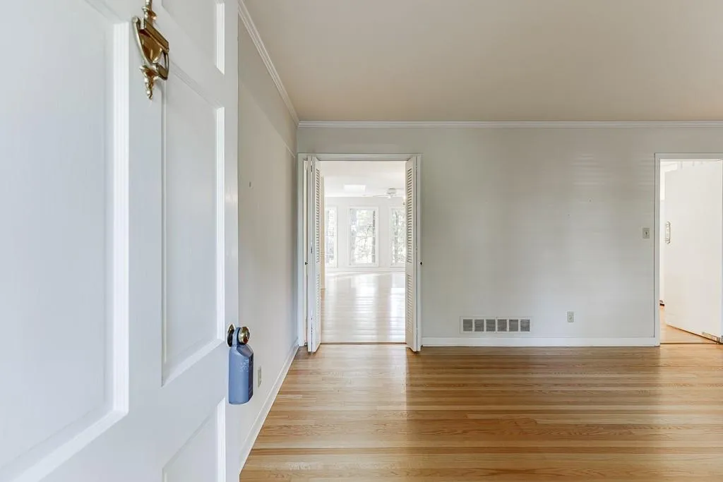 Unfurnished room with crown molding, baseboards, visible vents, and light wood-type flooring