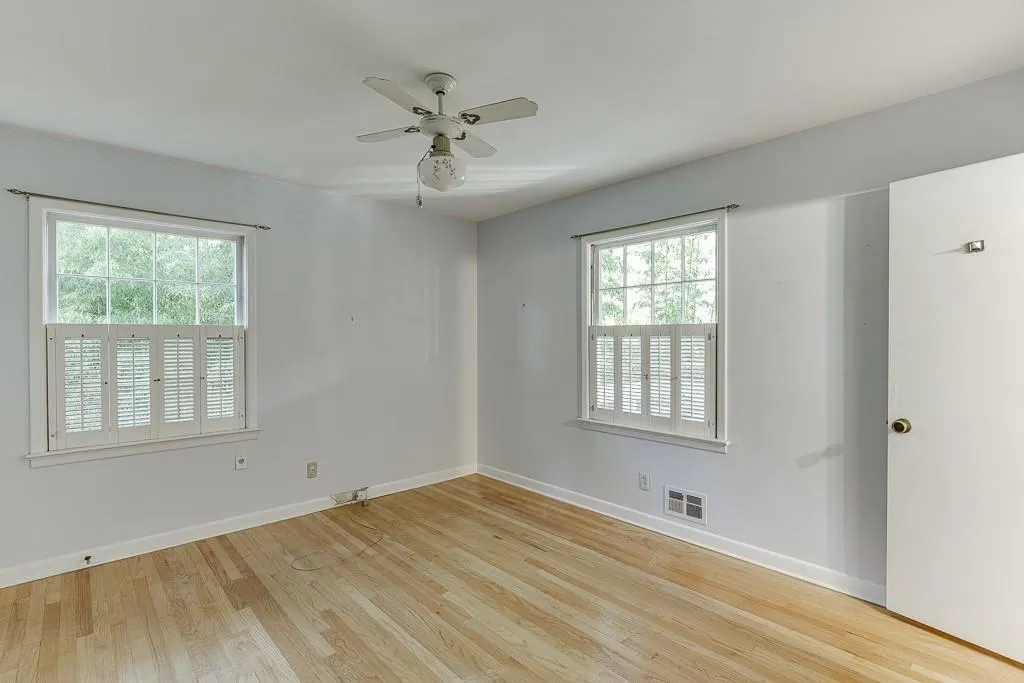 Spare room with visible vents, plenty of natural light, baseboards, and wood finished floors