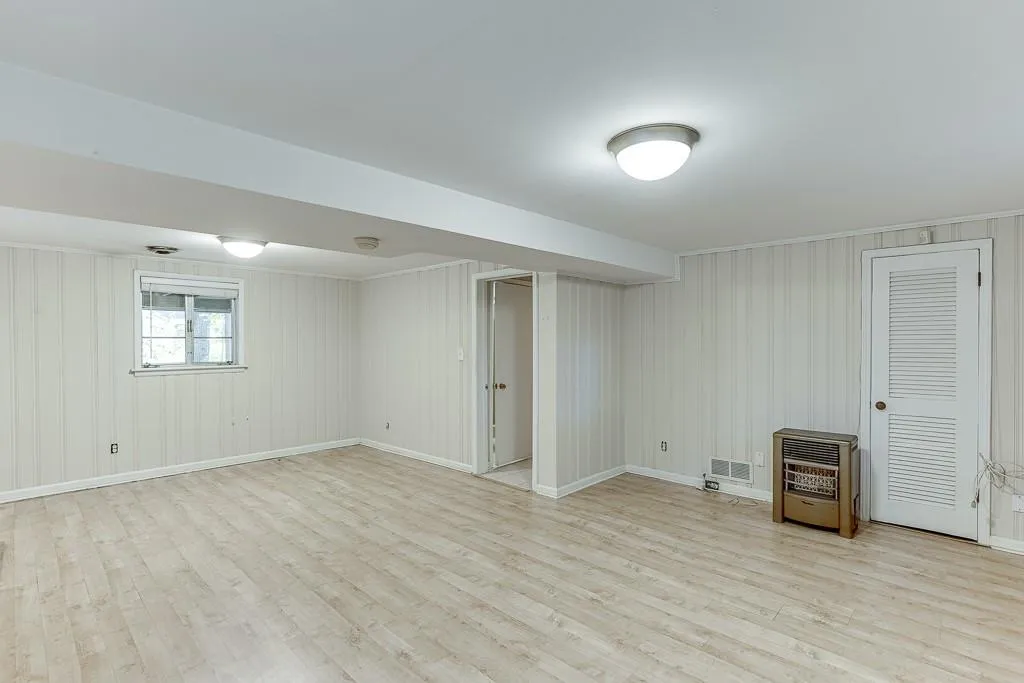Basement with heating unit, wood finished floors, and baseboards