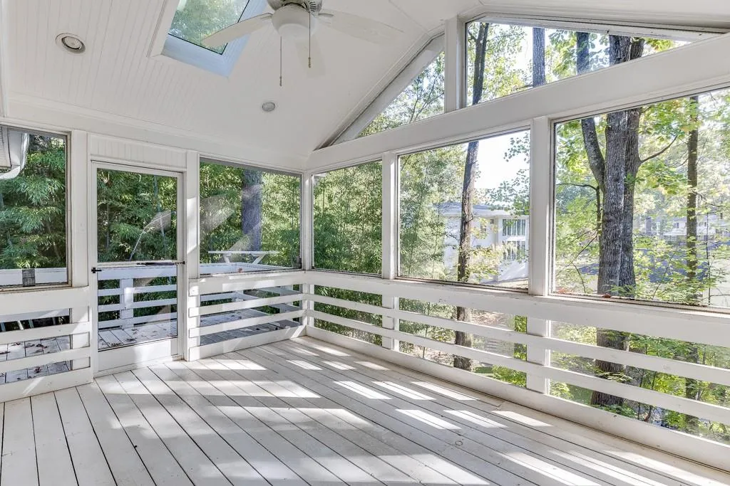 Unfurnished sunroom with lofted ceiling with skylight and a ceiling fan