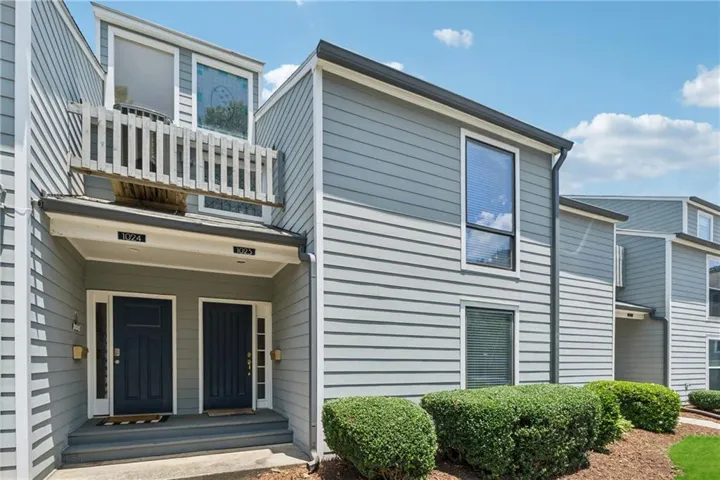 Siding exterior with multiple windows, individual entry doors, and an upper-level balcony