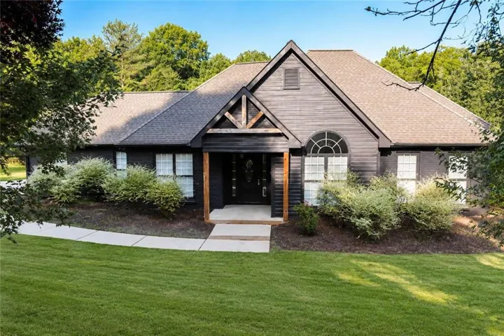 Contemporary home featuring a striking peaked roofline with decorative timber accents, complemented by a mixed-material exterior of board-and-batten siding and brick