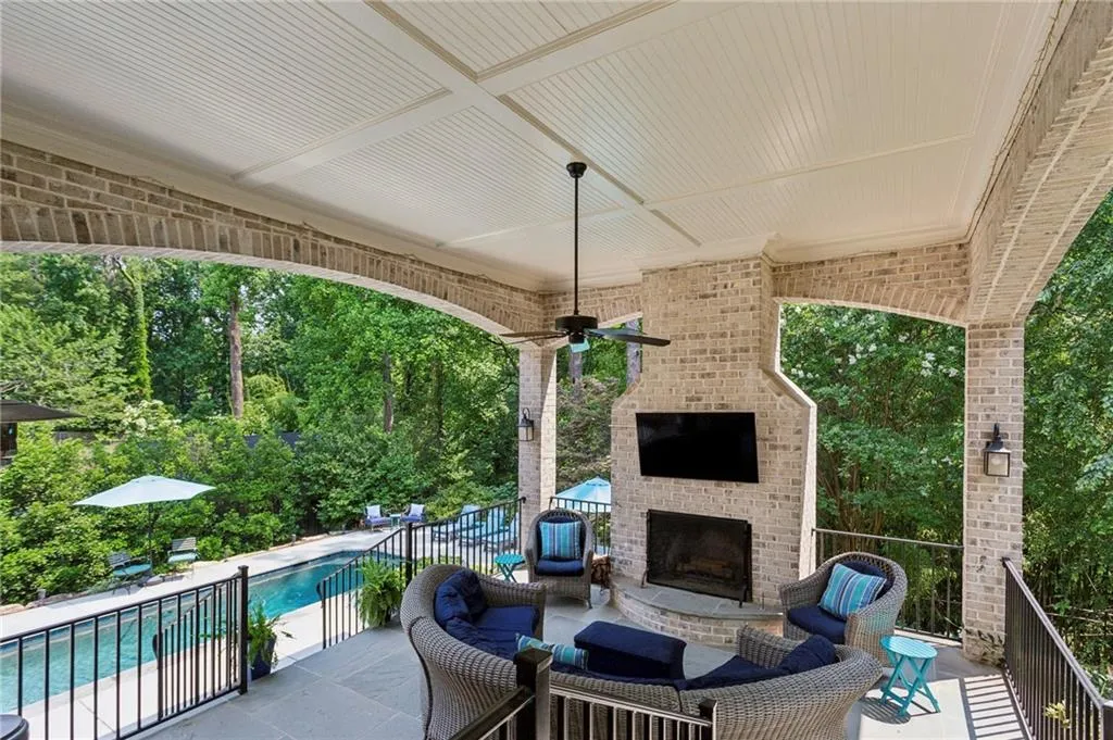 View of back porch with brick arches, blue stone floors, wood-burning fireplace and ceiling fan