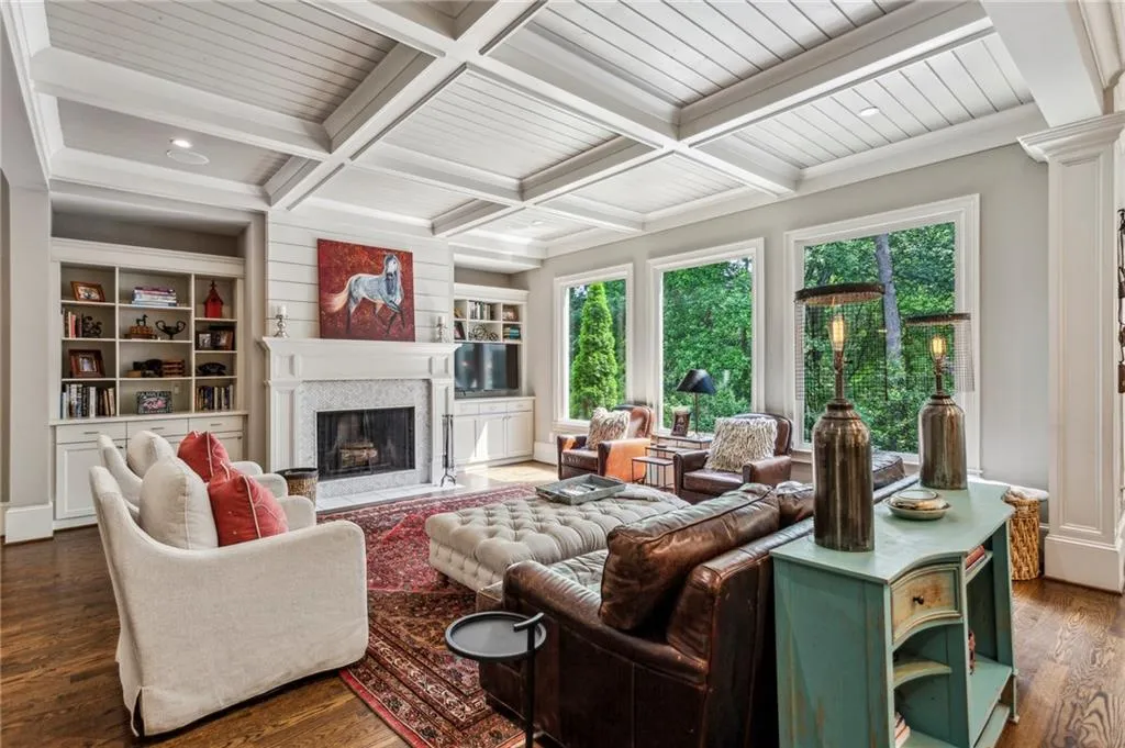 Large family room with a wood burning fireplace with flush hearth, built in cabinets and bookshelves, coffered ceiling