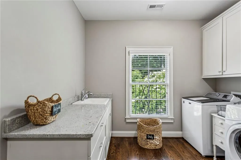 Second floor laundry room with cabinets, folding table, utility sink, washer and clothes dryer, healthy amount of natural light, and dark wood-style floors