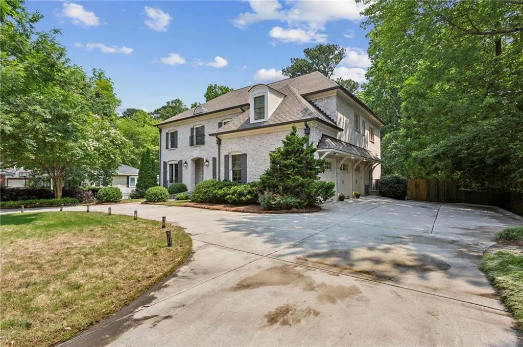 French country inspired facade featuring curved driveway, brick siding, and an attached 3-car garage