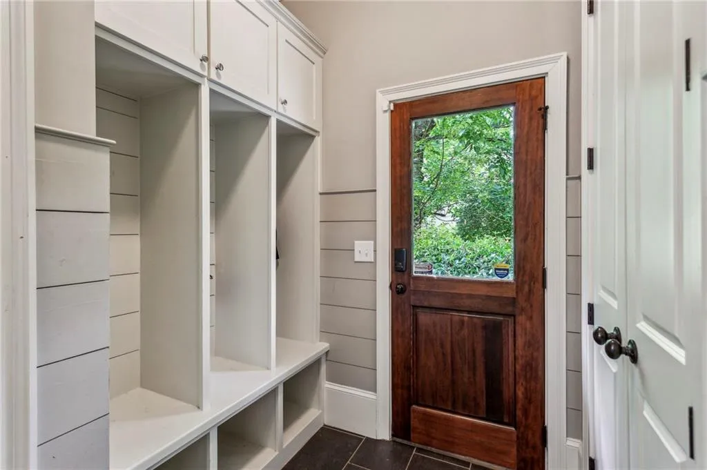 Mudroom featuring dark tile patterned flooring, cubbie, entrance to walk-in pantry, coat closet, door to the garage and side entry