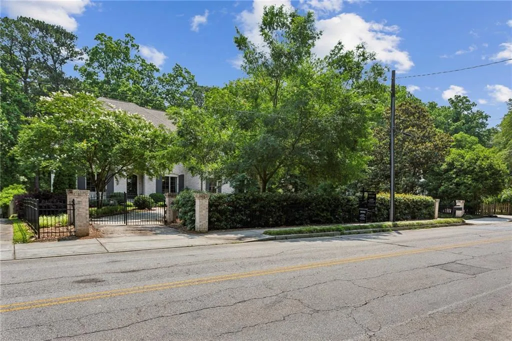 View of property hidden behind natural elements with a fenced front yard and a gate