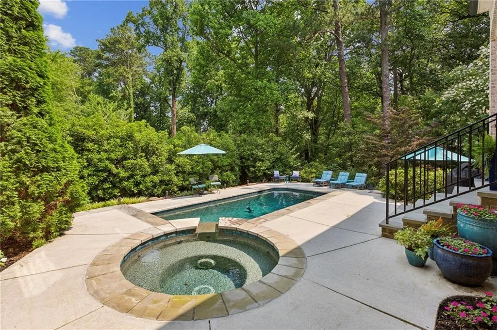 View of saltwater pool with a patio area, stairs, and a pool with connected spa