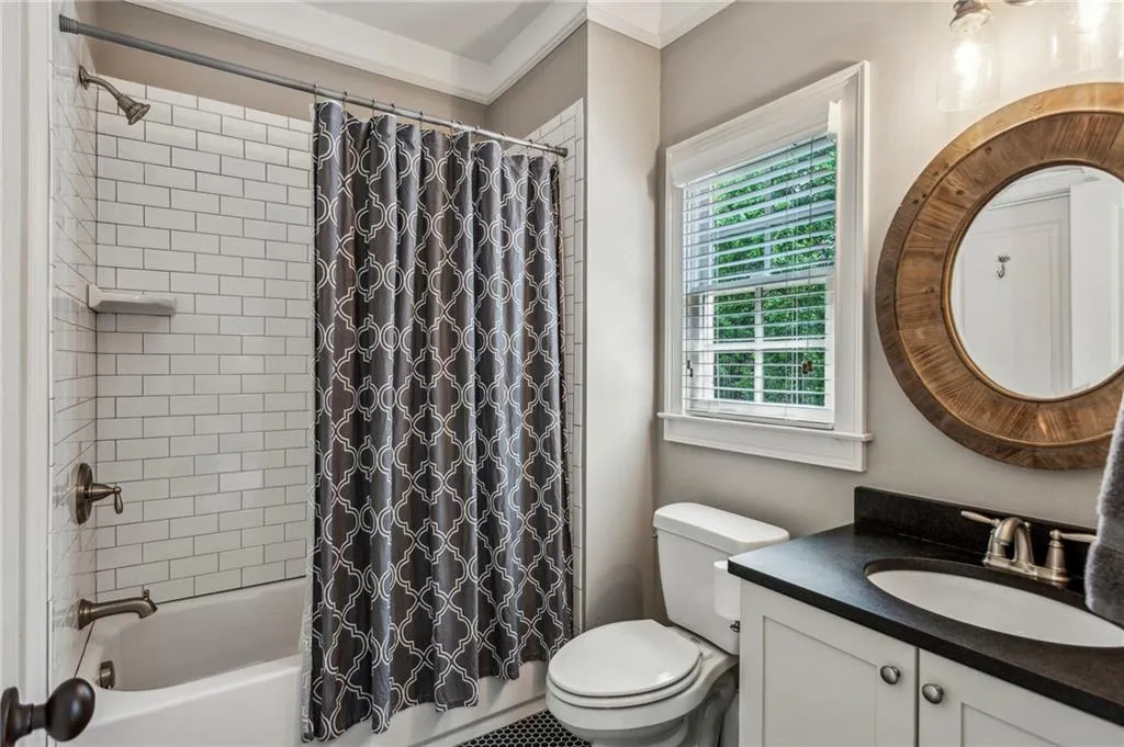 Private bathroom with vanity, shower / tub combo, toilet, and crown molding
