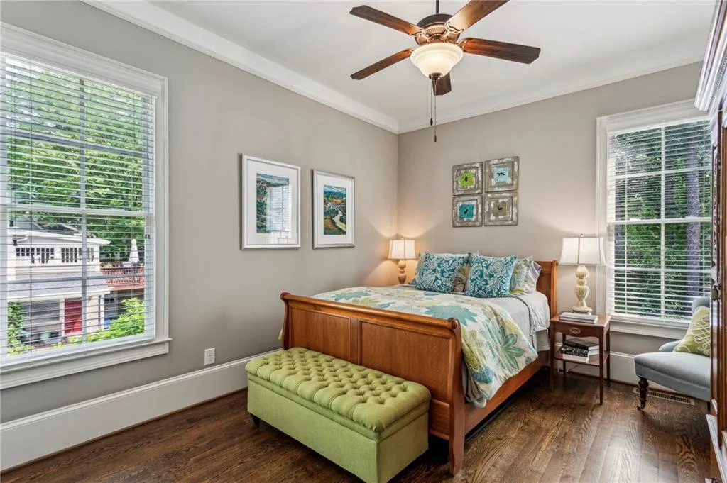 Bedroom on the main floor with multiple windows, dark wood-style flooring, crown molding, and baseboards - great for guest suite or private office