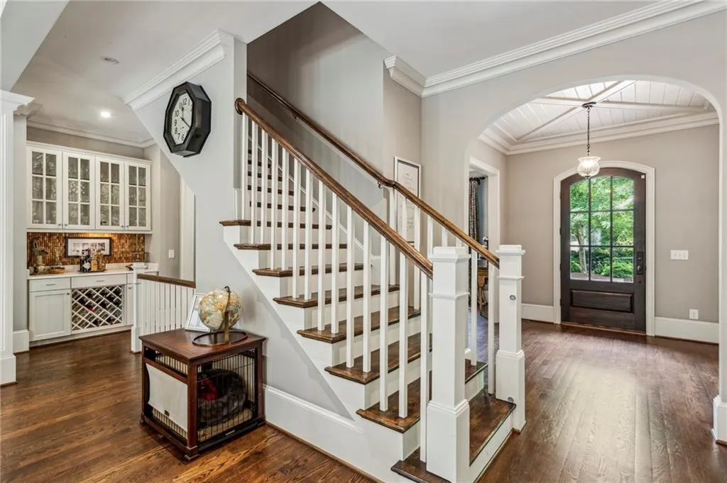 Foyer entrance featuring arched walkways, stairway, dark wood-style floors, baseboards, and crown molding
