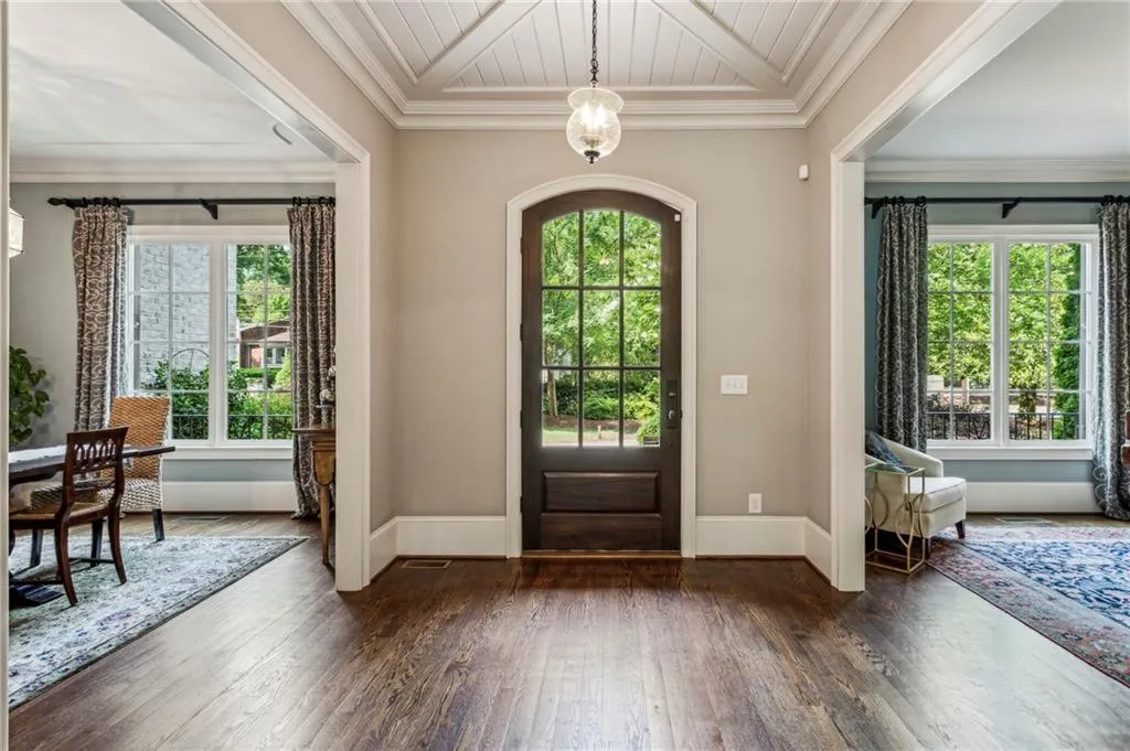 Foyer with plenty of natural light, hardwood floors, high baseboards, and detailed ornamental molding