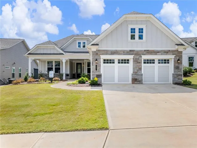 Craftsman-style exterior with stone and siding accents, a covered front porch, an attached two-car garage with carriage-style doors, and a concrete driveway