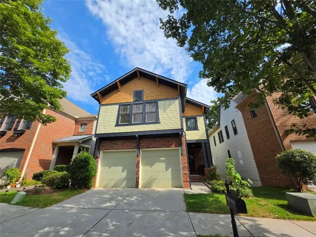 Two-story residence featuring a brick and siding exterior, dual garage doors, a concrete driveway, and mature landscaping
