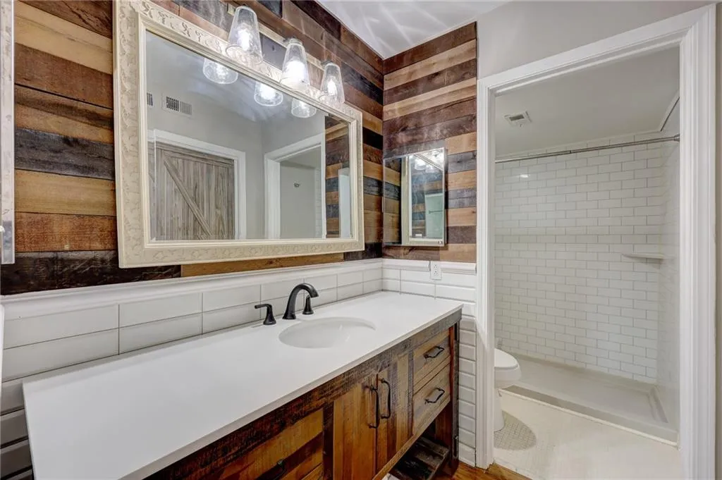 Full bathroom featuring vanity, tile walls, a shower stall, and tasteful backsplash