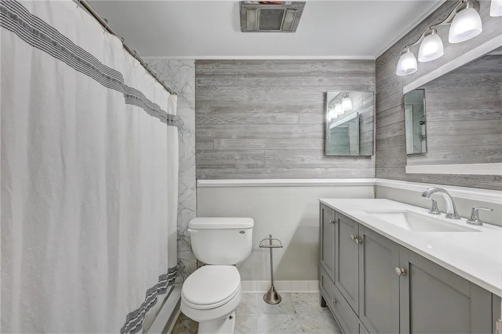 Bathroom featuring a shower with curtain, vanity, and wood walls