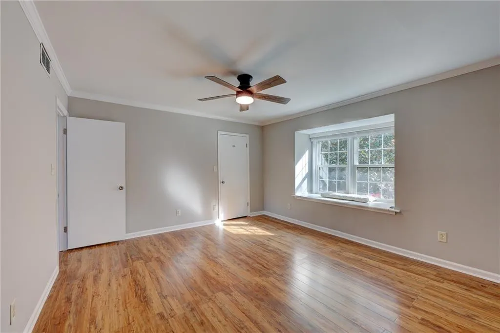 Unfurnished bedroom with ornamental molding, light wood-style flooring, and a ceiling fan