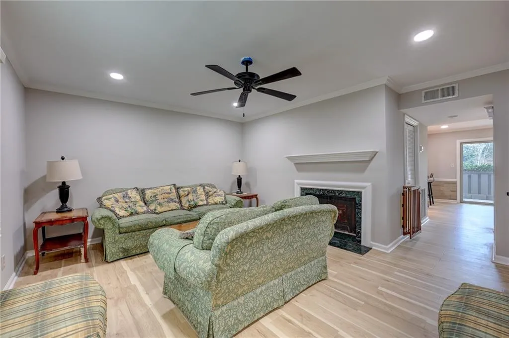Living area featuring light wood-type flooring, crown molding, a fireplace, recessed lighting, and a ceiling fan