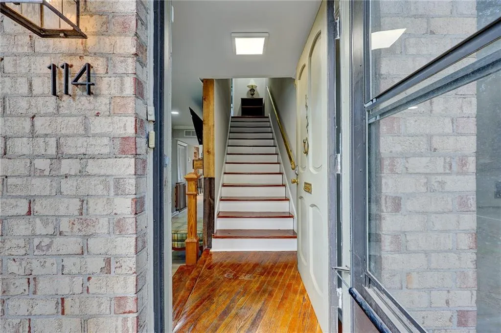 Stairway with hardwood / wood-style flooring and brick wall