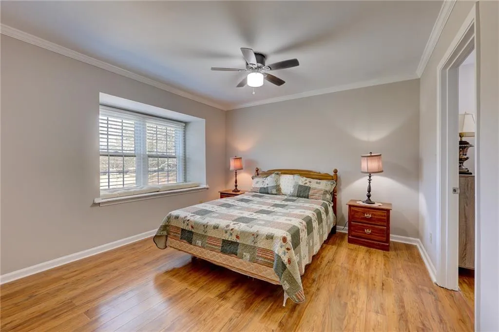 Bedroom with ornamental molding, light wood finished floors, and ceiling fan