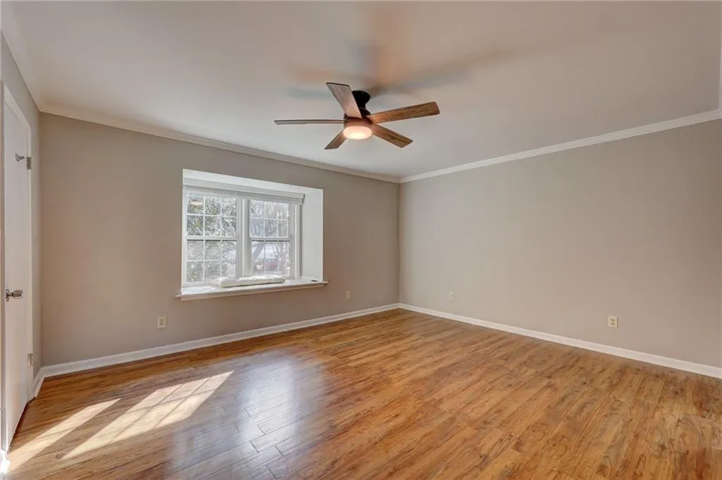 Unfurnished room featuring light wood finished floors, crown molding, and ceiling fan