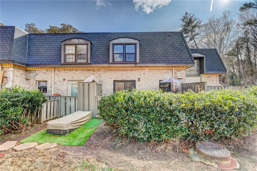 Rear view of property with mansard roof, brick siding, and a high end roof