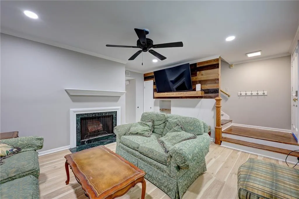 Living area featuring wood finished floors, recessed lighting, crown molding, stairway, and a premium fireplace
