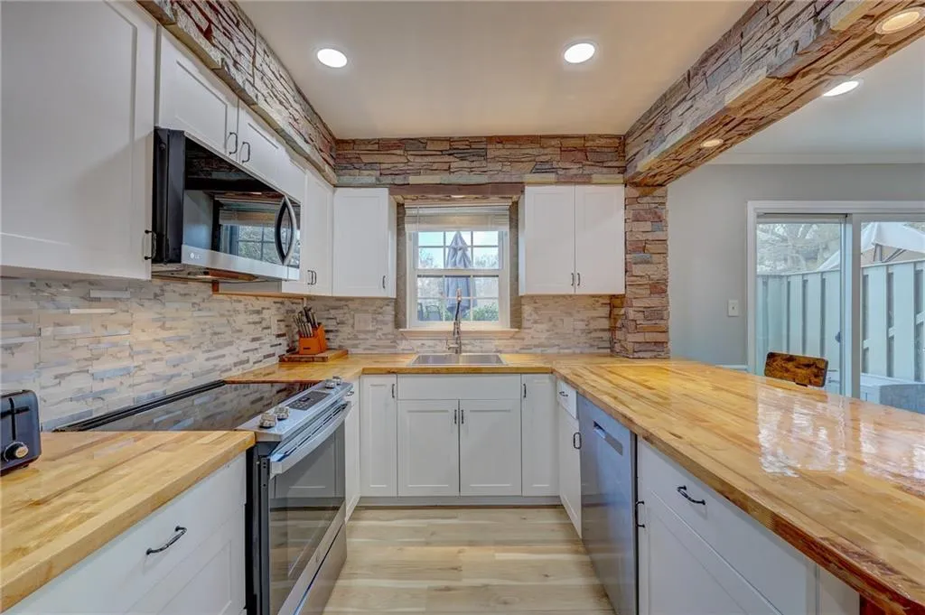 Kitchen featuring stainless steel appliances, butcher block counters, recessed lighting, and white cabinets