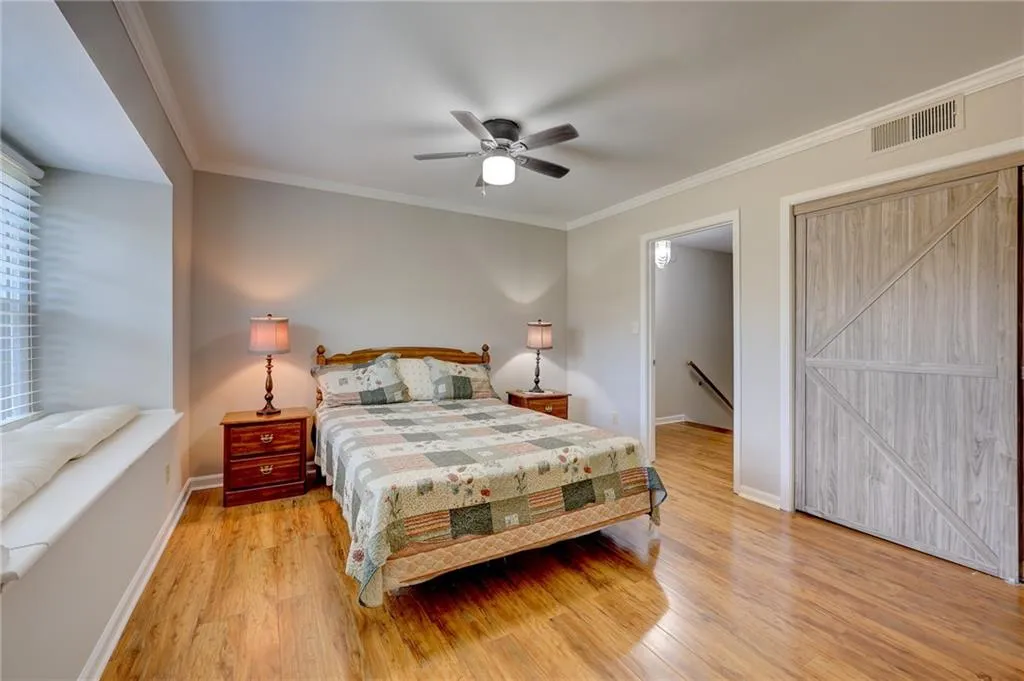 Bedroom featuring crown molding, light wood-style floors, and ceiling fan