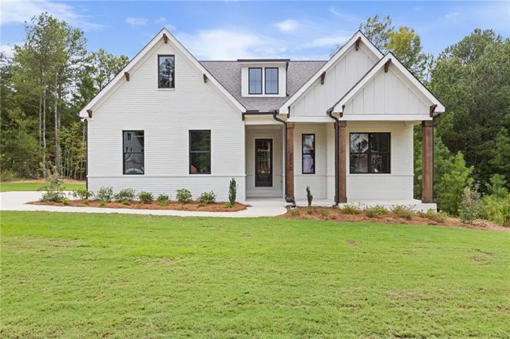 White brick exterior with board and batten accents, black-framed windows, and a covered entry with timber columns