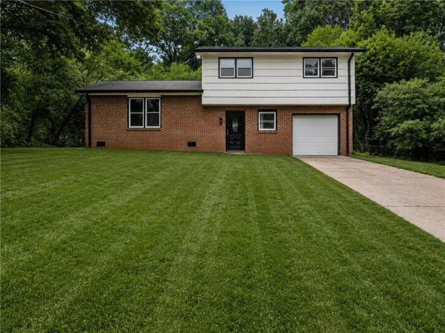 Welcoming brick and siding exterior with a two-story design featuring multiple windows and an attached single-car garage