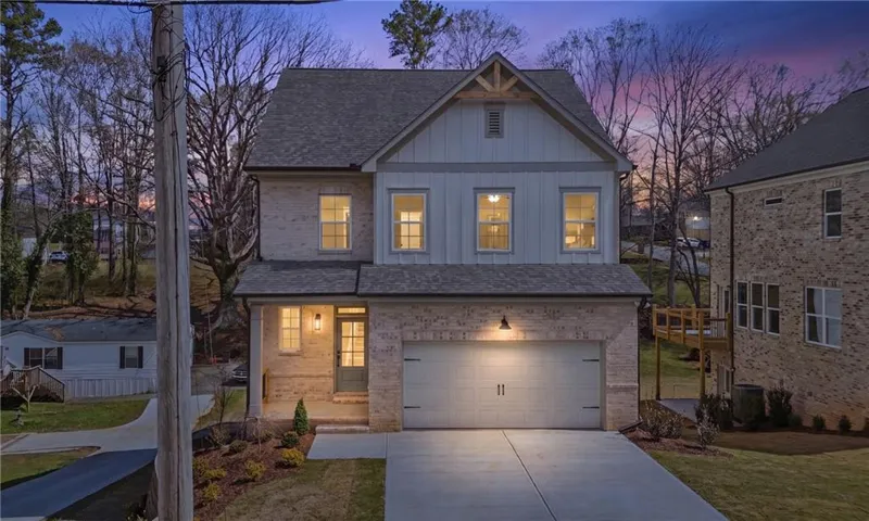 Two-story residence featuring a brick and board-and-batten facade, covered front porch, attached garage with carriage-style door, and concrete driveway