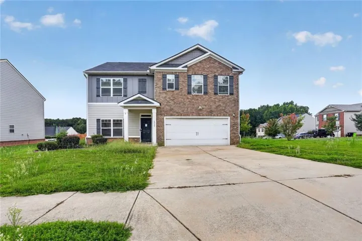 Two-story residence featuring a brick facade with siding accents, an attached garage, and a concrete driveway